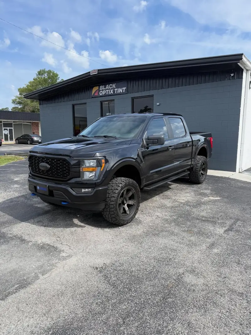 Lifted black Ford F-150 tinted outside the Wilmington shop
